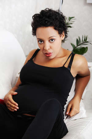 Young pregnant woman sitting on sofaの写真素材