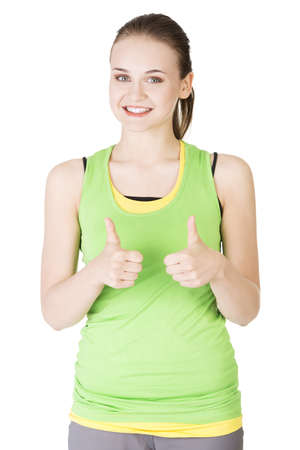 Attractive fitness woman in sport clothes gesturing thumbs up, isolated on white の写真素材