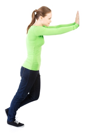 Woman pushing something imaginary isolated over a white background (white wall over her hands) の写真素材