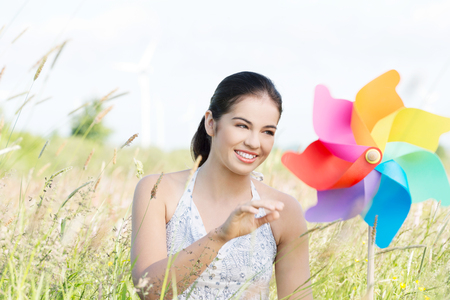Beautiful young woman with windmill. Standing outdoor.の写真素材