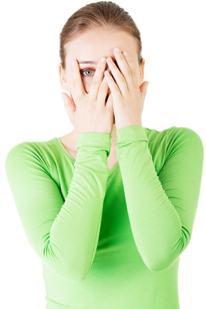 Attractive woman covering her face with both hands. Isolated on white. の写真素材