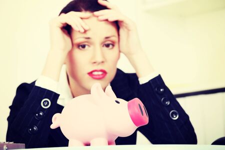 Pretty caucasian businesswoman in depression with piggy bank.の写真素材