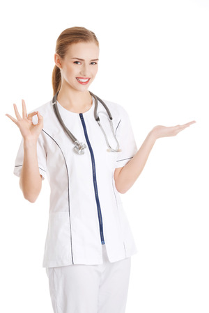 Beautiful caucasian doctor or nurse is presenting an abstract space. Isolated on white.の写真素材