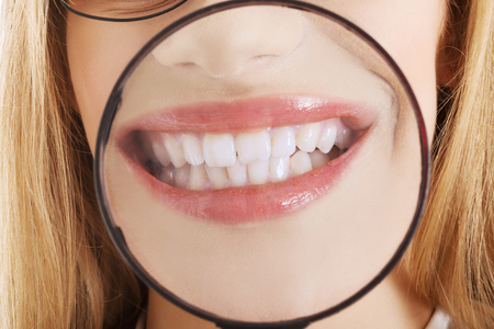 Close up on business woman's teeth through magnyfying glass.の写真素材