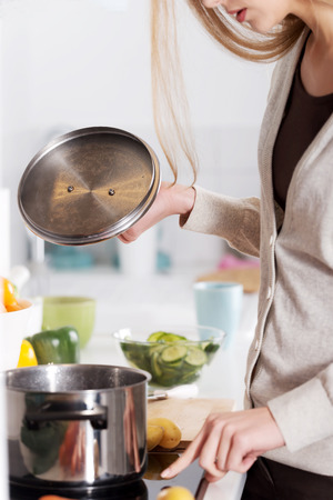 Beautiful caucasian woman is cooking. Kitchen background.の写真素材