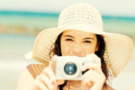 Attractive cheerful summer woman talking pictures with digital camera .