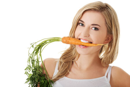 Happy young woman with the carrotsの写真素材
