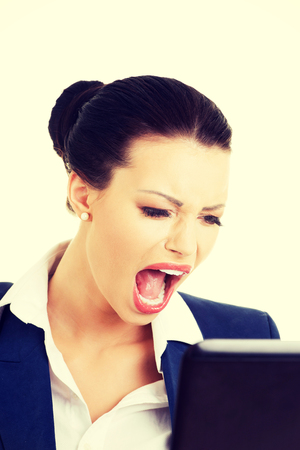 Angry businesswoman shouting on her laptop, isolated on whiteの写真素材