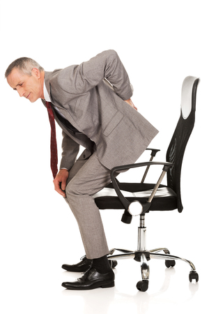 Businessman with backache standing up from a chair.の写真素材
