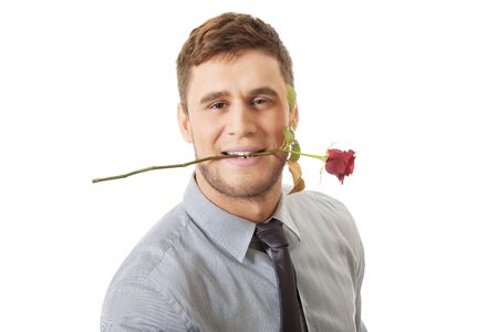 Young handsome man holding red rose in his mouth.の写真素材