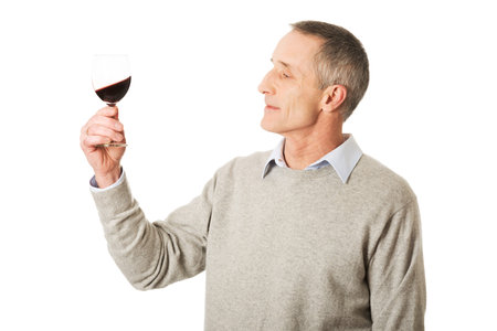 Handsome mature man tasting red wine.
