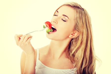 Smiling woman eating healthy salatの写真素材