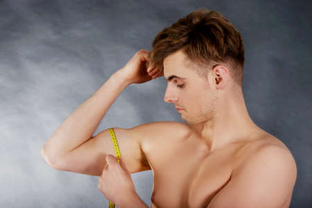 Young fitness man measuring his biceps.の写真素材