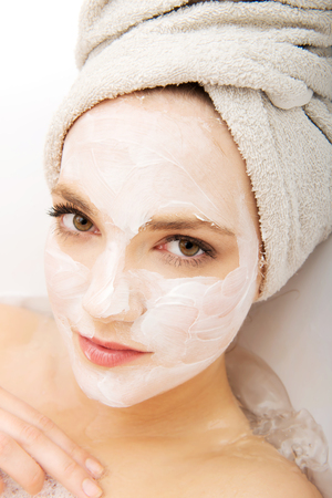 Young spa woman relaxing in bathtub with cream moisturizer.の写真素材