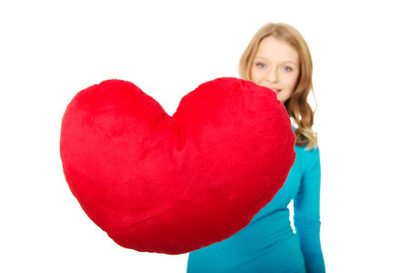 Happy teenage woman with heart shaped pillowの写真素材