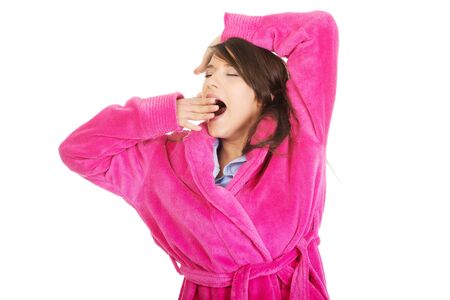 Beautiful stretching and yawning woman wearing pink bathrobe.の写真素材