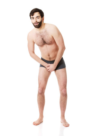 Young shirtless man holding his crotch because of pain.の写真素材