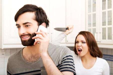 Young rage woman hitting her talking partner with frying pan.の写真素材