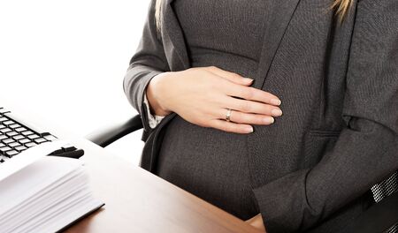 Pregnant woman touching her belly in the officeの写真素材