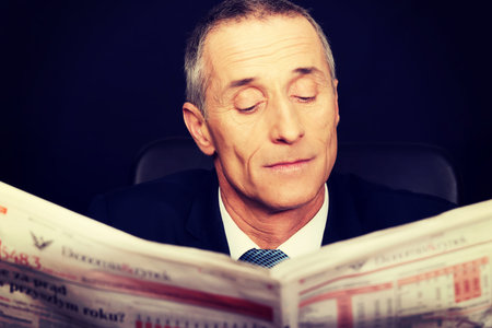 Matre businessman reading a newspaper in the office.の写真素材