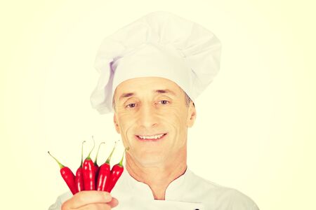 Male chef in uniform holding chilli peppersの写真素材
