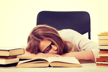 Exhausted teenage woman sleeping on the deskの写真素材