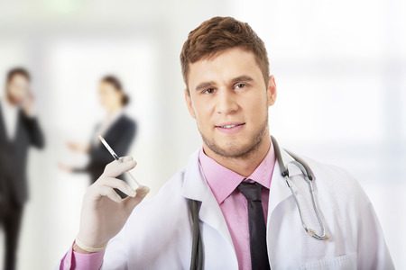 Handsome male dentist doctor holding a syringe.の写真素材