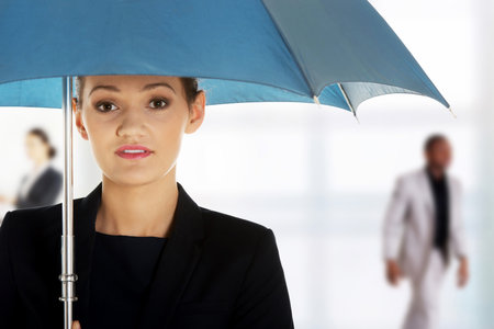 Beautiful business woman is holding blue umbrella.の写真素材