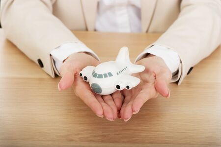 Business woman by a desk holding a toy plane.の写真素材