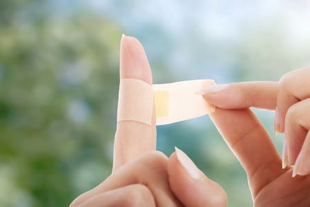 Woman using adhesive tape on finger.の写真素材