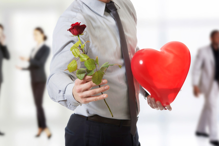 Young handsome man with a red rose and heart balloon.の写真素材