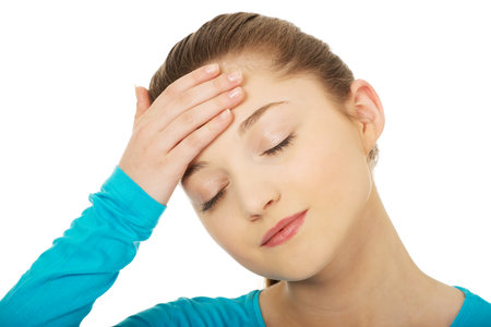 Teen woman with headache holding her head.の写真素材