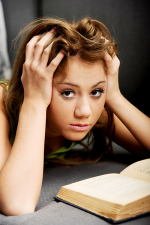 Young teenage woman learning to exam on a sofa.の写真素材