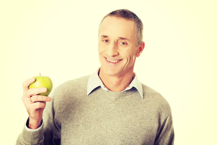 Smiling mature man with an apple.の写真素材
