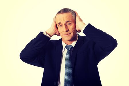 Portrait of tired businessman covering ears with hands.の写真素材