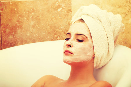 Relaxing woman with closed eyes and cream lotion on faceの写真素材