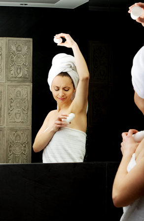 Woman using deodorant in the bathroom.の写真素材