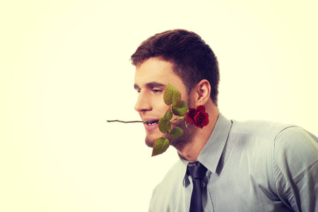Young handsome man holding red rose in his mouth.の写真素材