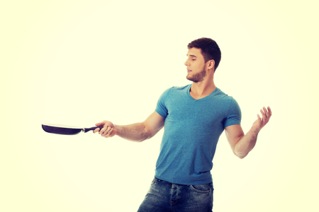 Handsome muscular man holding frying pan.の写真素材
