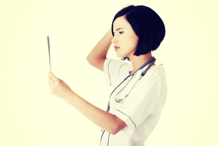 Worried female doctor analysing x-ray image.の写真素材