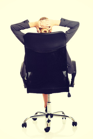 Businesswoman resting on armchair holding her neckの写真素材