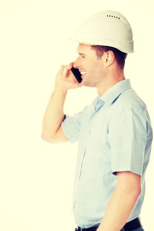 Contractor in hardhat smiles as he talks on his cell phone.の写真素材