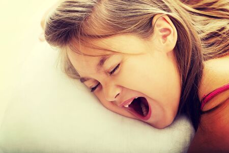 Pretty young girl yawning while waking upの写真素材