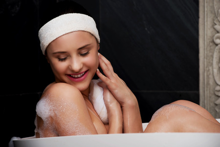 Beautiful bathing woman relaxing in bathtub with sponge.の写真素材