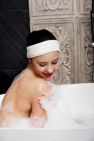 Beautiful bathing woman relaxing in bathtub.