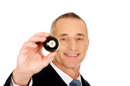 Businessman holding billiard eight ball in his hand.