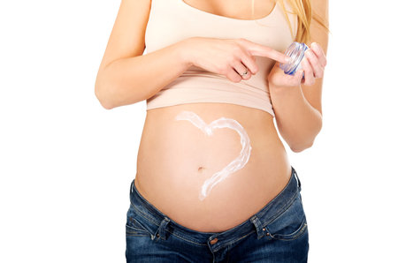 Pregnant woman with heart shape on belly made from cream