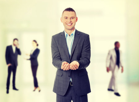 Happy man in suit showing copy space with his handの写真素材