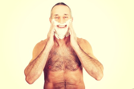 Happy mature man applying shaving foam.の写真素材