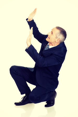 Frightened businessman protecting himself from empty space.の写真素材